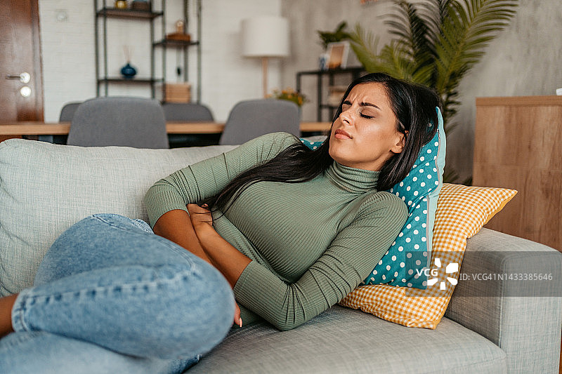 年轻女人在家中经期痉挛图片素材