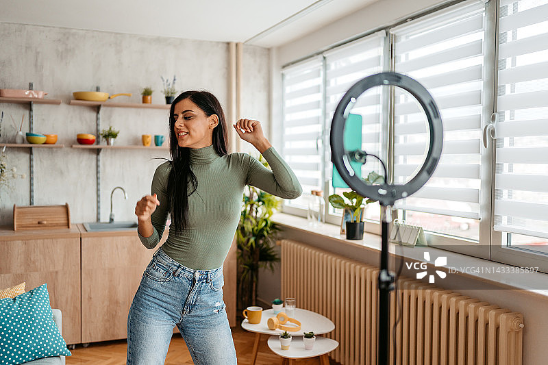年轻女人在家拍摄自己跳舞的视频图片素材