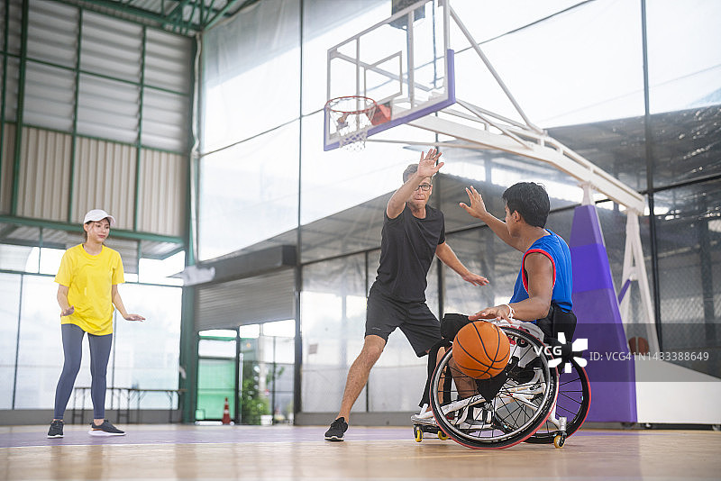 坐在轮椅上的男人在运动场上和朋友打篮球图片素材
