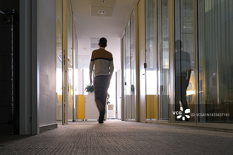 商业环境——商务男士走在办公室的走廊里图片素材