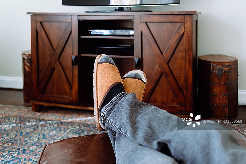 在电视前放松，脚放在脚凳上的男人图片素材