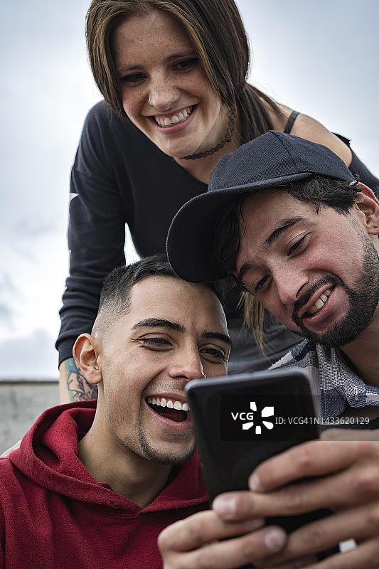 一群滑板朋友在滑板公园看智能手机图片素材