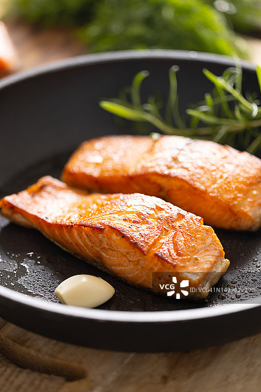 黑色煎锅中的三文鱼片和香草图片素材