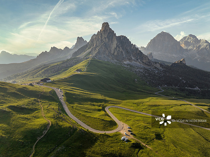 多洛米蒂阿尔卑斯山夏季日落美景：徒步者在绿色山丘附近的全景航拍图片素材