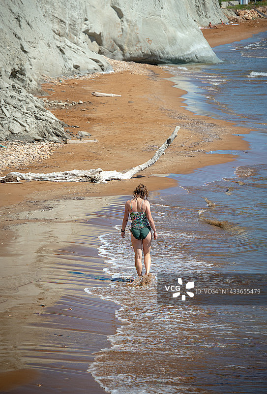 穿着泳衣的女人走在海滩上，希腊凯法利尼亚图片素材