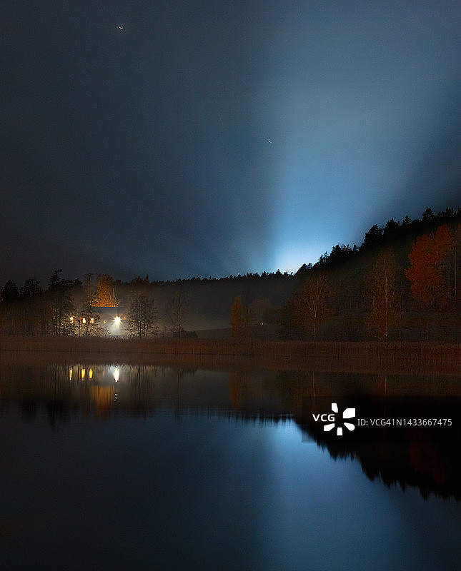 房屋、光线和雾蒙蒙的秋季森林被海景环绕，夜间群岛风光。芬兰西部。北欧图片素材