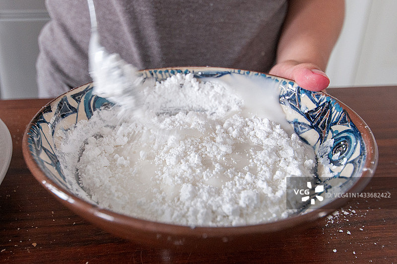 木制厨房台面上，碗中糖粉与水混合图片素材