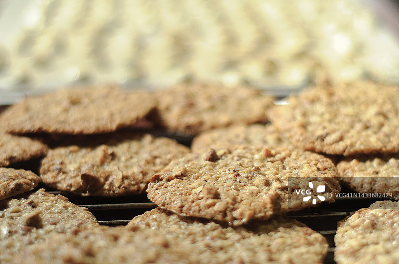 金棕色家常烘焙饼干特写，背景有浅色甜点。图片素材