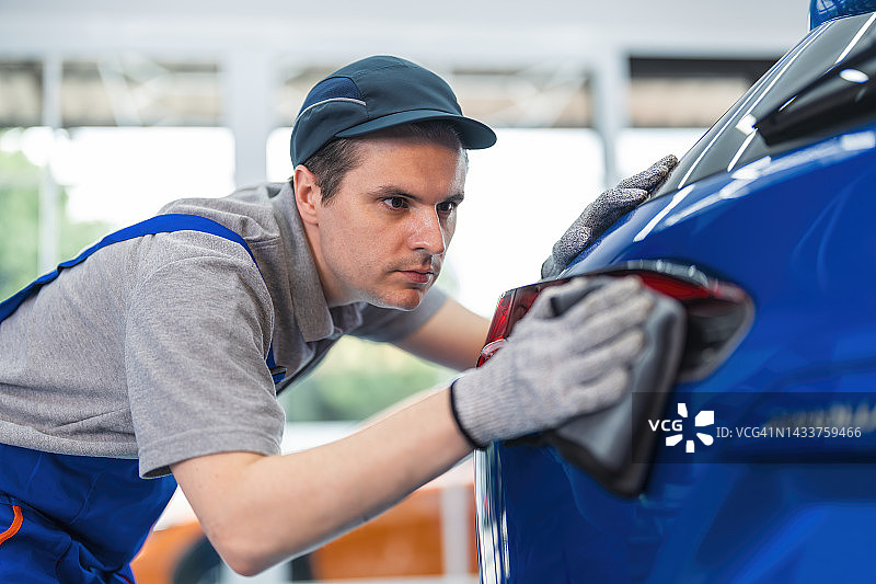 男人用超细纤维布擦拭汽车外部图片素材