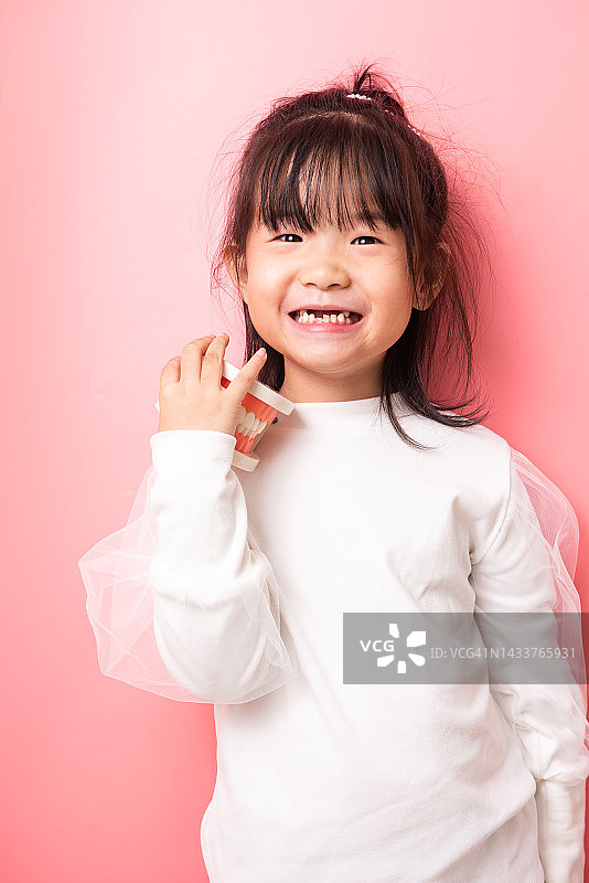 手拿牙齿模型的小女孩，牙科概念图片素材