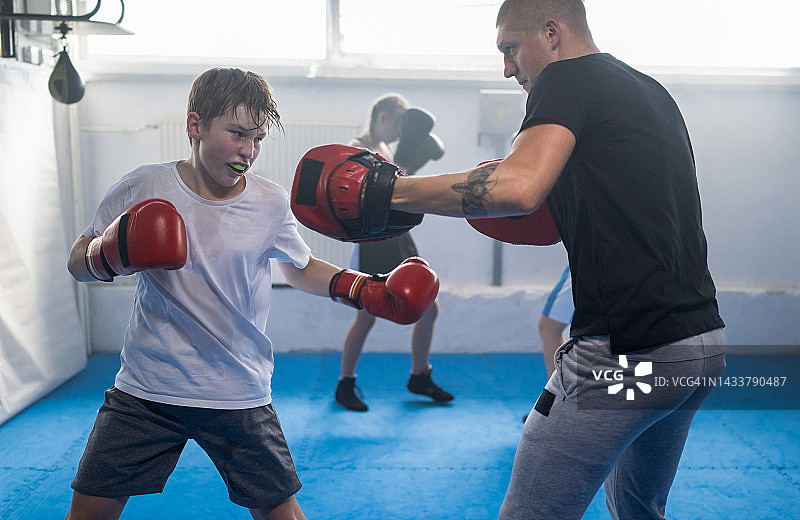 一群孩子在健身房与教练一起练习拳击图片素材