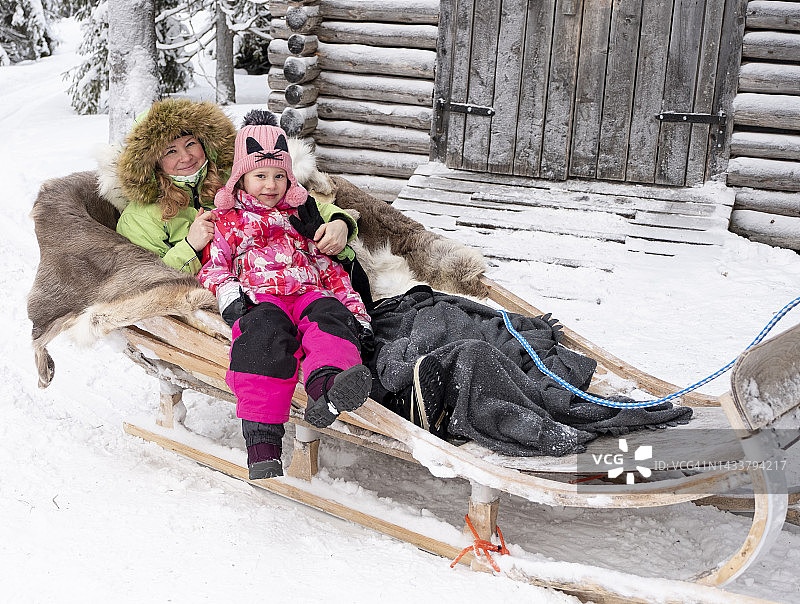 乘坐雪橇的一家人，驯鹿骑行。一位6岁的白人女孩和一位妇女的肖像图片素材