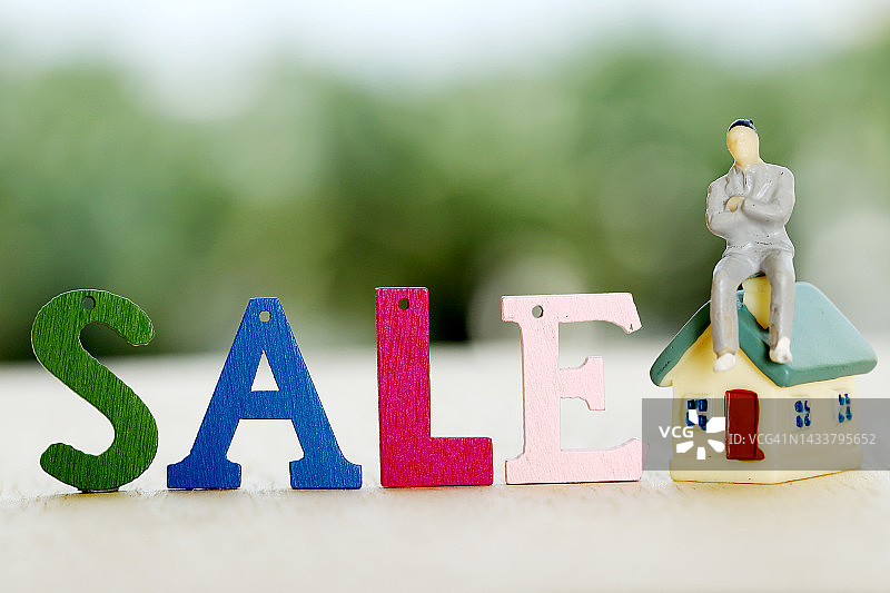 微型模型房产与绿色背景上的“销售”字样图片素材