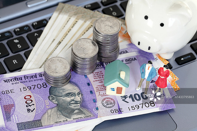 印度货币、小猪存钱罐和模型房在笔记本电脑键盘上图片素材