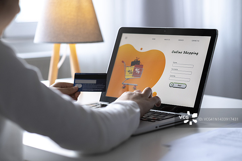 年轻女子手持信用卡和笔记本电脑图片素材