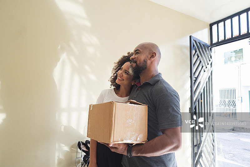 成年夫妇手捧纸箱走进新家图片素材