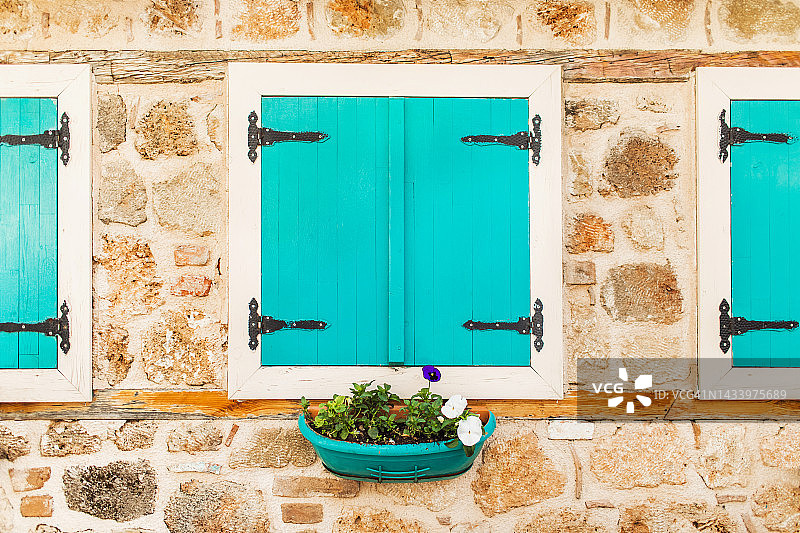 石材建筑立面和带有木制百叶窗及花盆的蓝色窗户图片素材