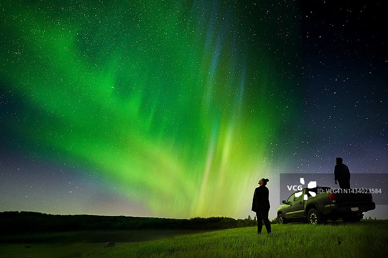 情侣站在皮卡旁观看北极光图片素材