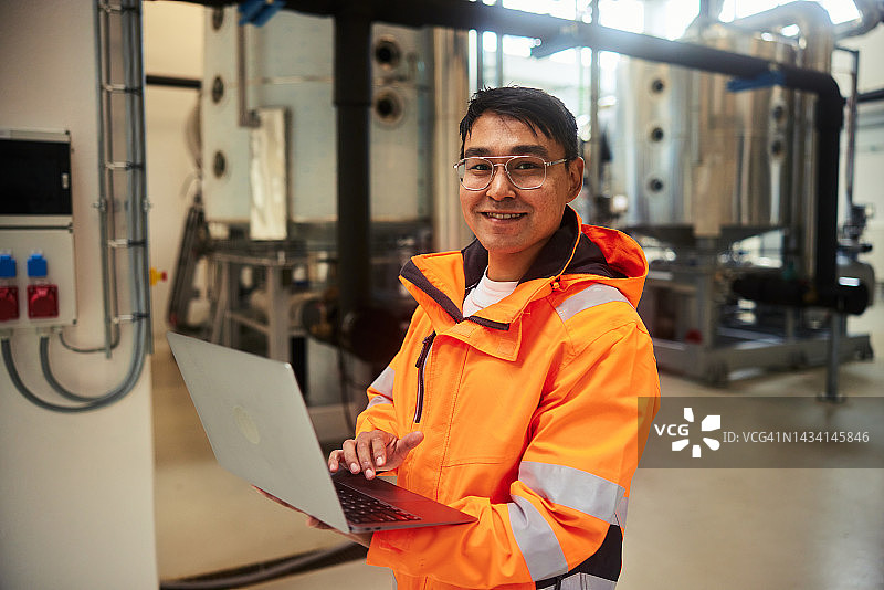 在发电站使用笔记本电脑的微笑年轻工程师图片素材