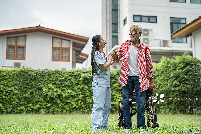 护理人员陪同老人在户外散步图片素材