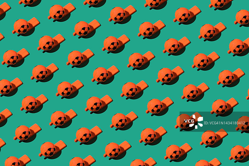 绿色背景上的橙色足球形塑料哨子图案图片素材