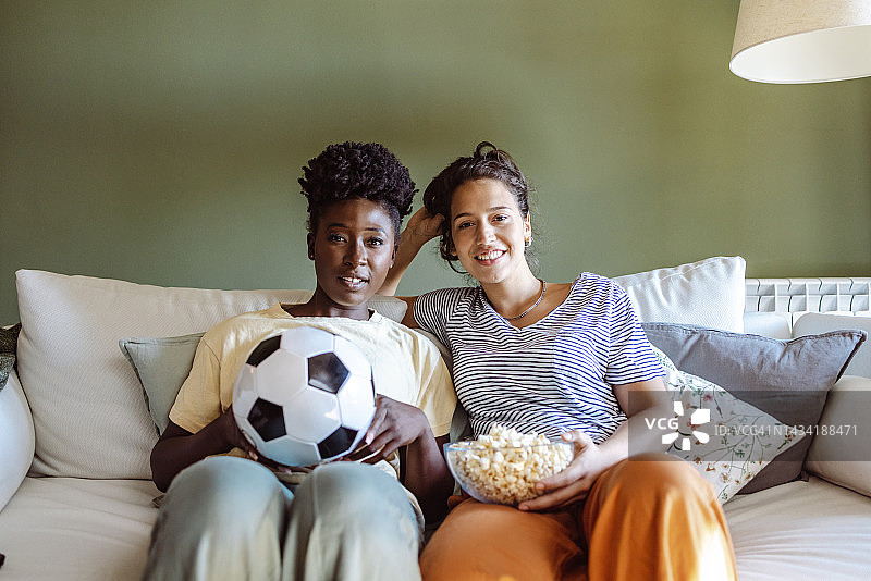 笑容满面的女性朋友们在电视上看足球比赛，为她们的运动队欢呼图片素材