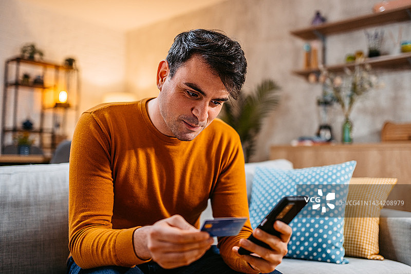年轻男人在家用手机网上购物图片素材