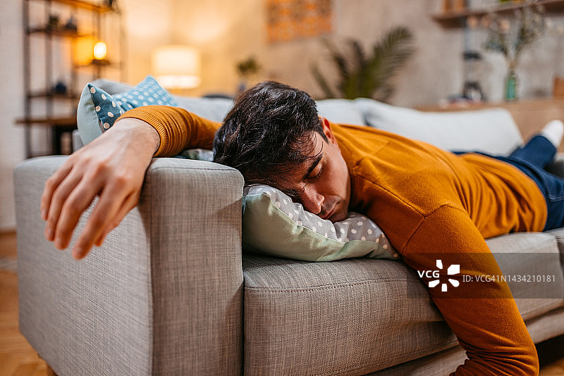 疲惫的年轻男子在沙发上睡觉图片素材