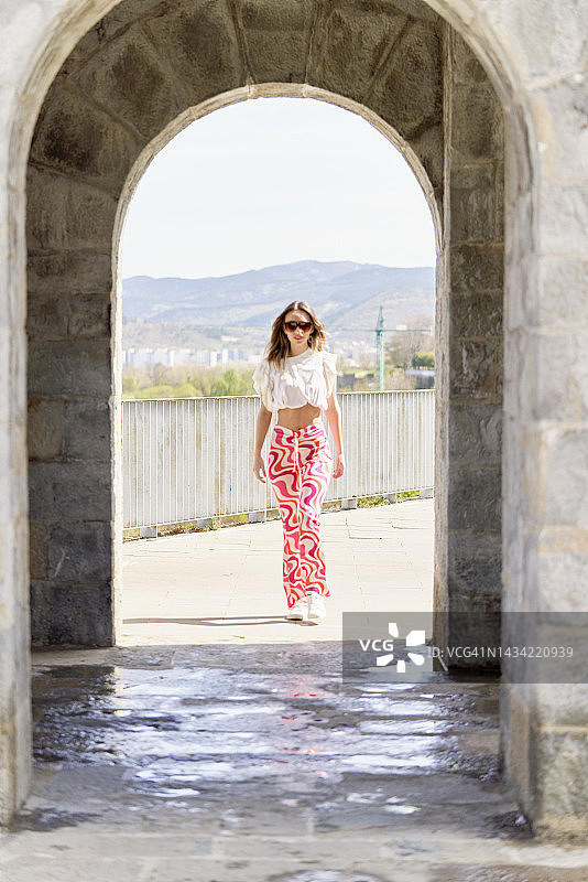 戴着太阳镜，走向桥入口，看着镜头的女人图片素材