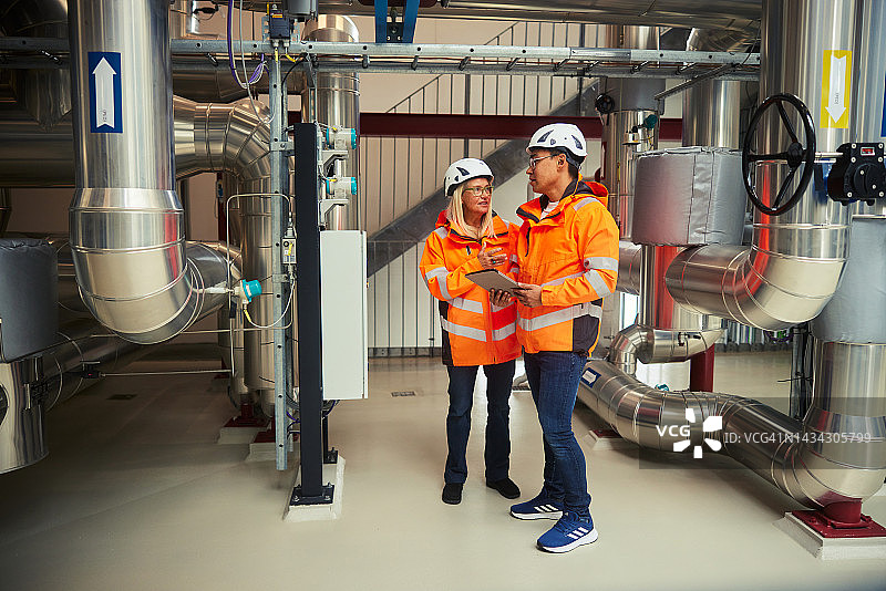 电力站内工程师在平板电脑上协同工作图片素材