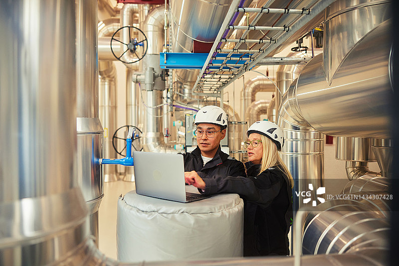 工程师在电站管道旁使用笔记本电脑图片素材