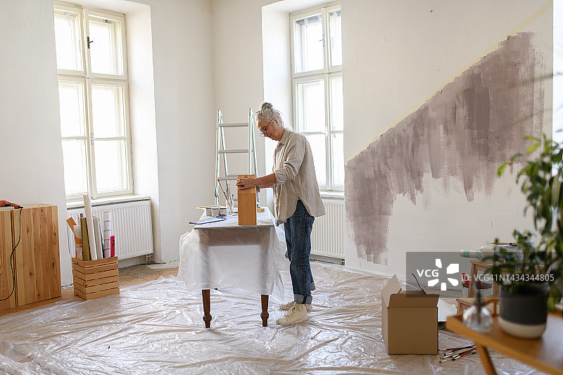 老年妇女粉刷小木柜图片素材