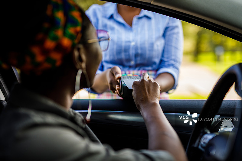 女人坐在车里，在汽车餐厅付款图片素材