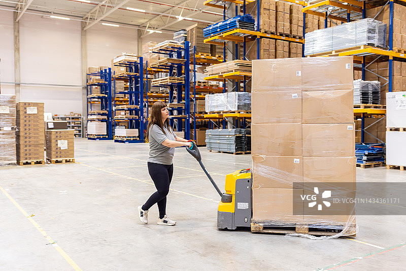 工人用托盘车搬运堆叠的包裹图片素材