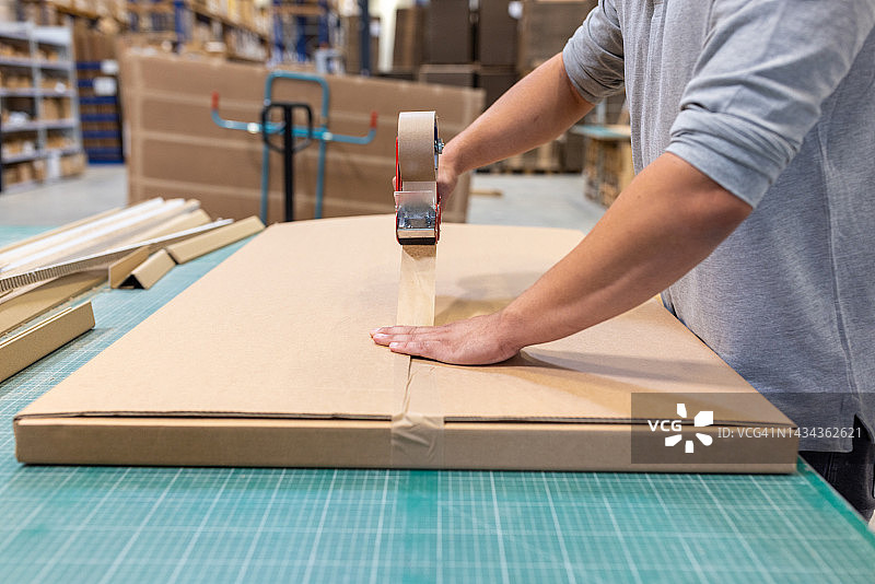 仓库工人用胶带在工厂里封纸箱特写图片素材
