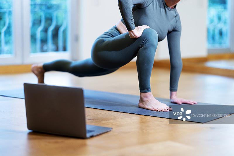 年轻女人在家通过视频会议练习普拉提图片素材