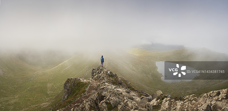 在英国湖区崎岖地形中徒步的孤独女子图片素材