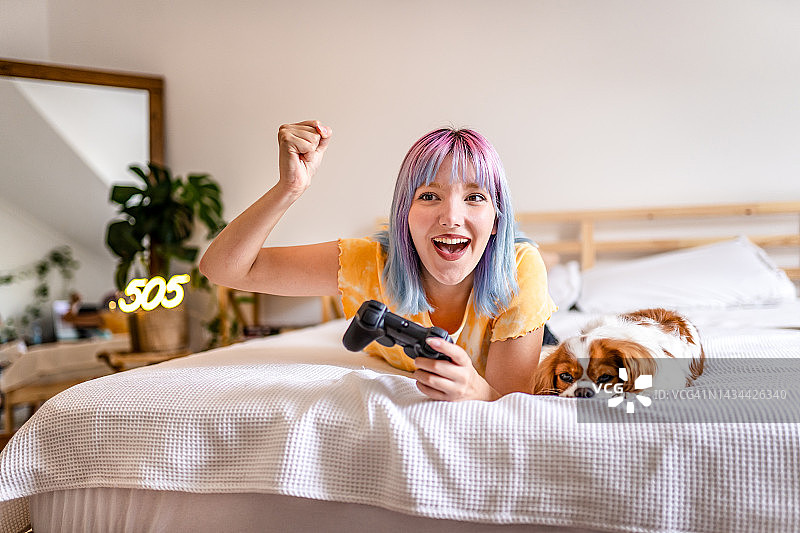 在房间里玩游戏的彩色头发的年轻女人图片素材
