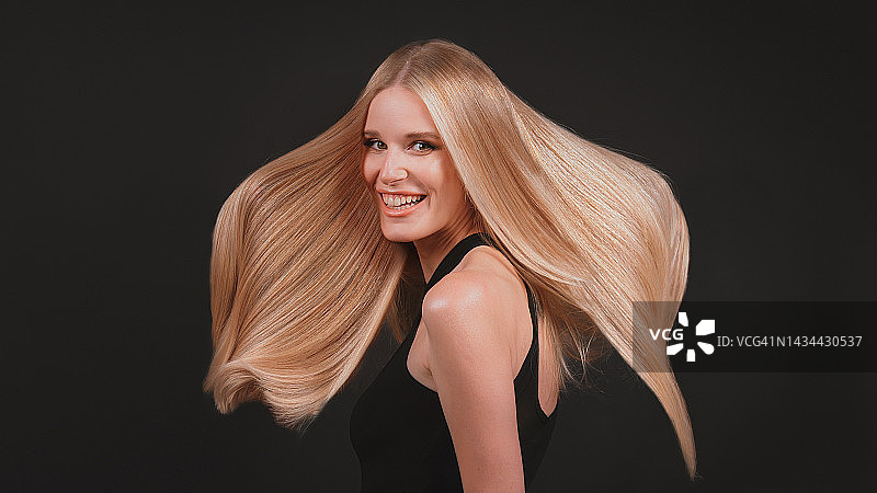 深色背景下风中飘逸金发的女人图片素材