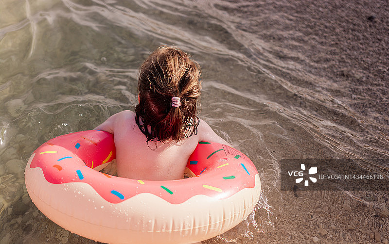 海滩上拿着充气泳圈的女孩特写图片素材