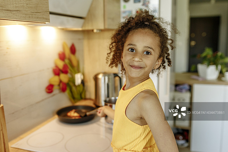 在厨房里做薄煎饼的微笑女孩图片素材