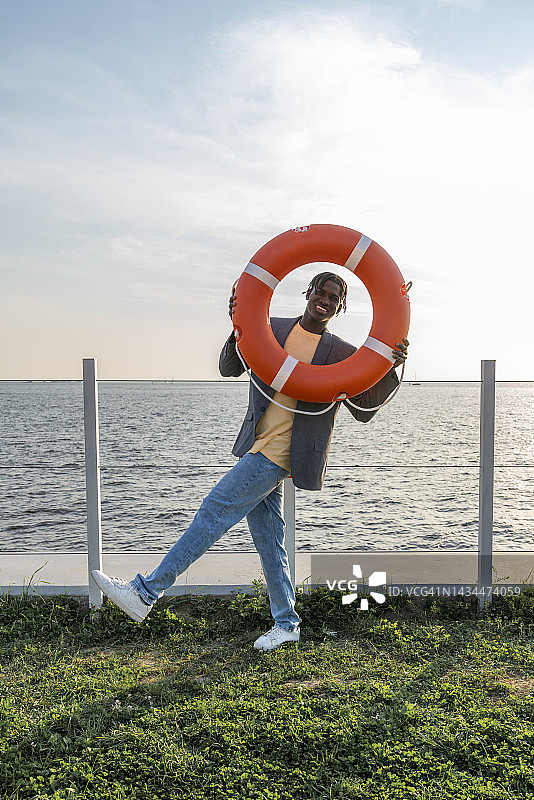 快乐的商人透过救生圈看日落图片素材