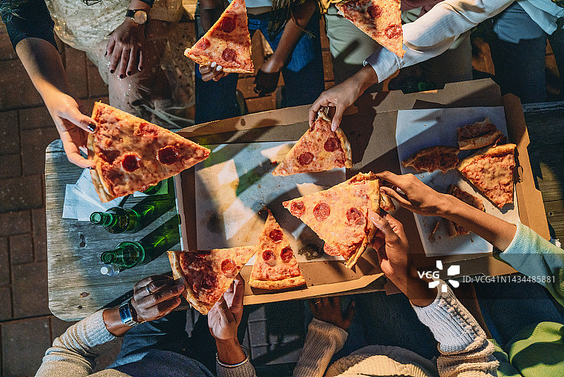 与朋友的晚餐派对 - 人们拿披萨片的高角度视图图片素材