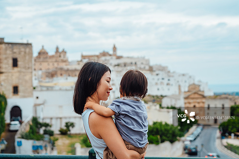 年轻的亚洲母亲带着幼儿女儿前往意大利普利亚大区奥斯图尼旅行。图片素材