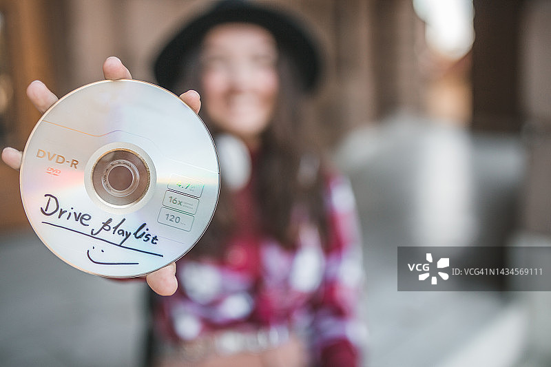 女士手持CD光盘，驾车时聆听音乐特写图片素材