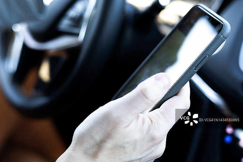 男人坐在驾驶座上使用智能手机图片素材