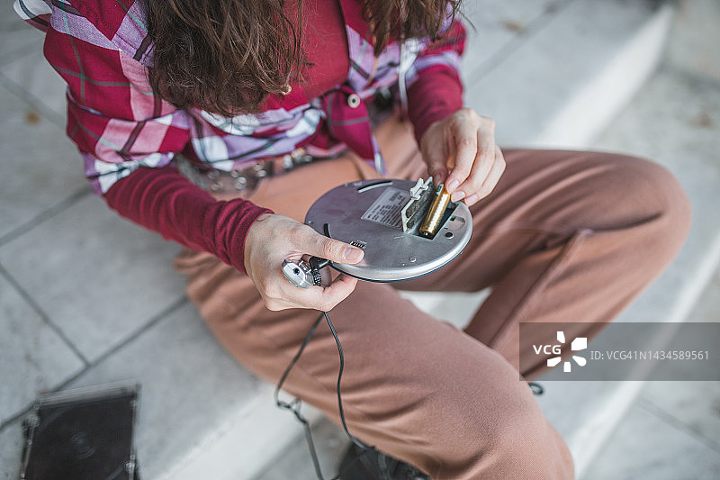 年轻女子将电池装入CD机特写图片素材