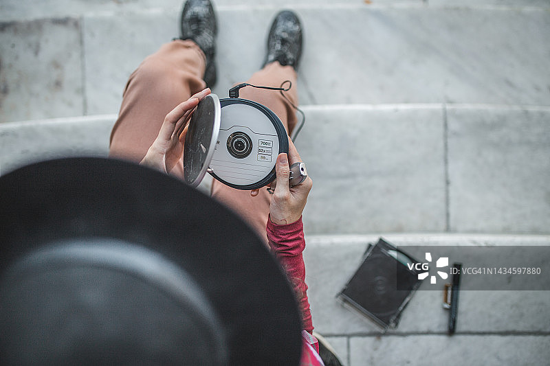 戴着帽子的女子将光盘放入迷你光盘播放器（高角度）图片素材