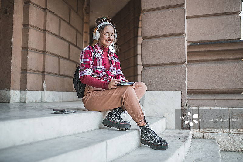 坐在楼梯上用CD机听音乐的美丽女人图片素材