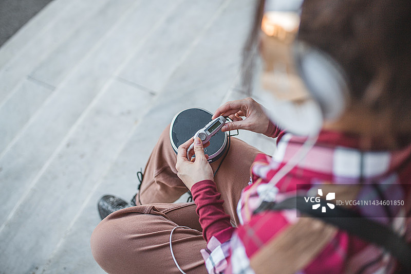 年轻女人坐楼梯听音乐背影图片素材